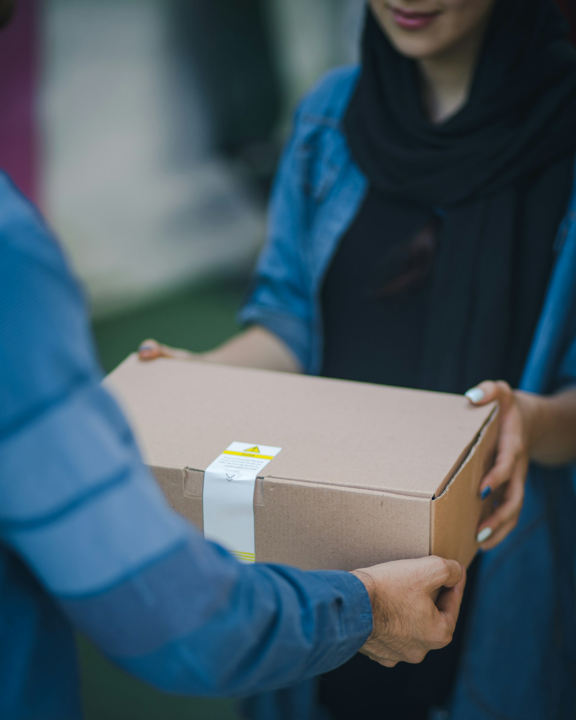 A person handing over a brown cardboard box