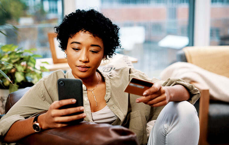 Young African-American woman with her credit card in one hand and mobile phone in the other